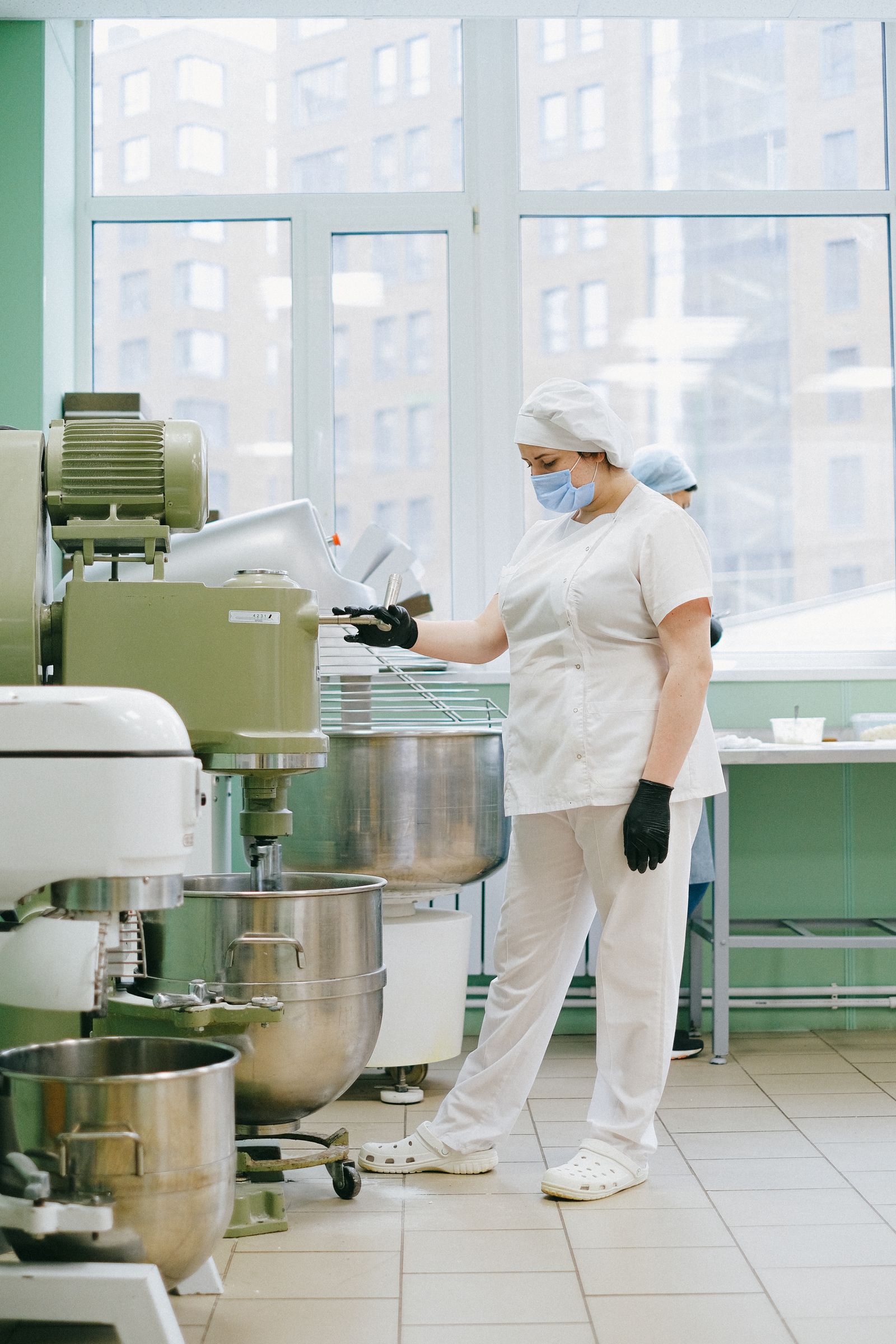 Operaria con uniforme y mascarilla operando un equipo en planta de alimentos